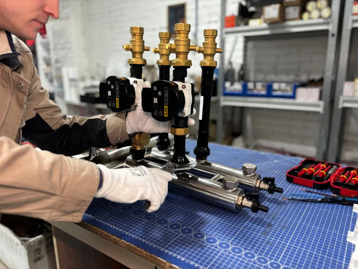Engineer assembling heating pipework and valves on a bench