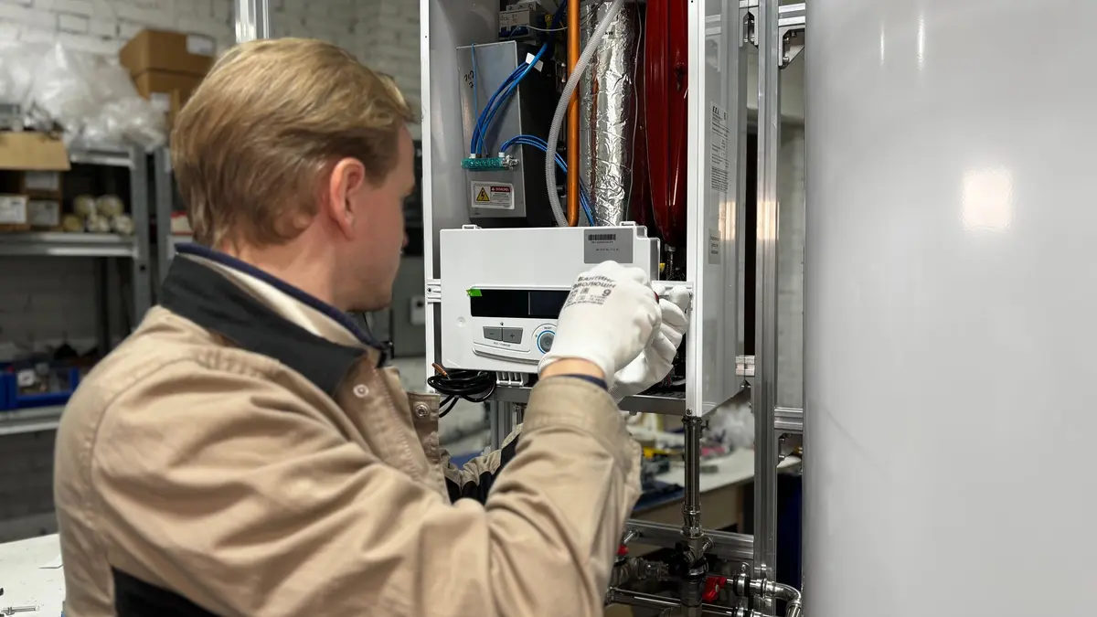 Heating engineer checking a wall-hung boiler in a workshop